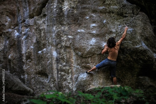 bouldering  climber on a vertical wall on the way to the top