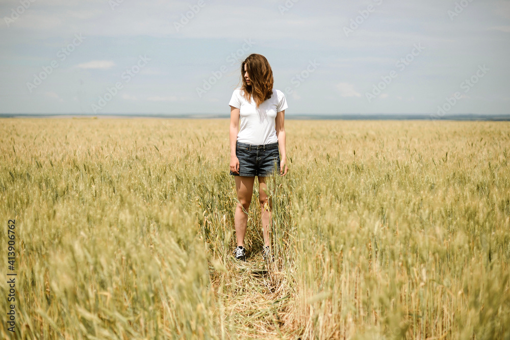 Young woman stands in a wheat field in summer Young woman stands in a wheat field in summer