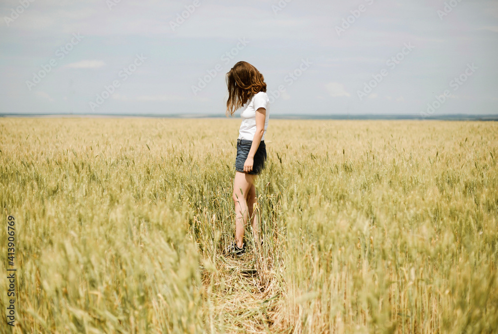 Young woman stands in a wheat field in summer Young woman stands in a wheat field in summer