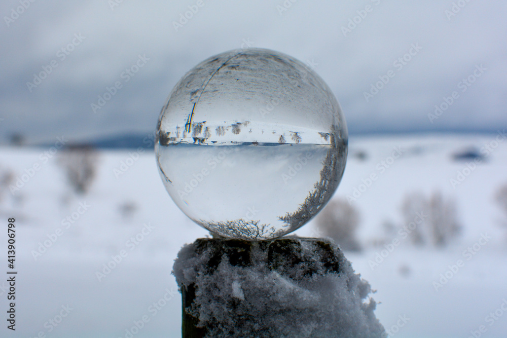 Snow-covered landscape is reflected in a glass