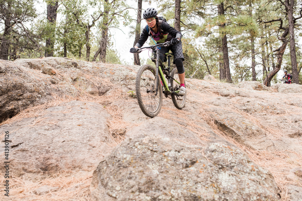 Female mountain biker riding down rocky trail Female mountain biker riding down rocky trail