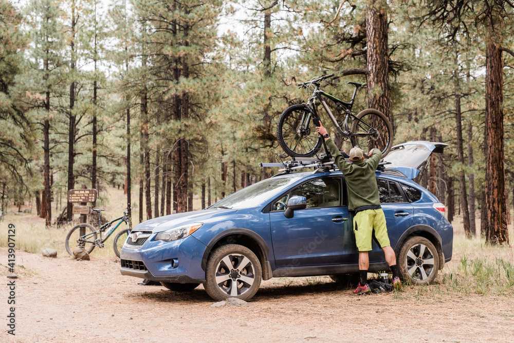 Man taking mountain bike down from car Man taking mountain bike down from car