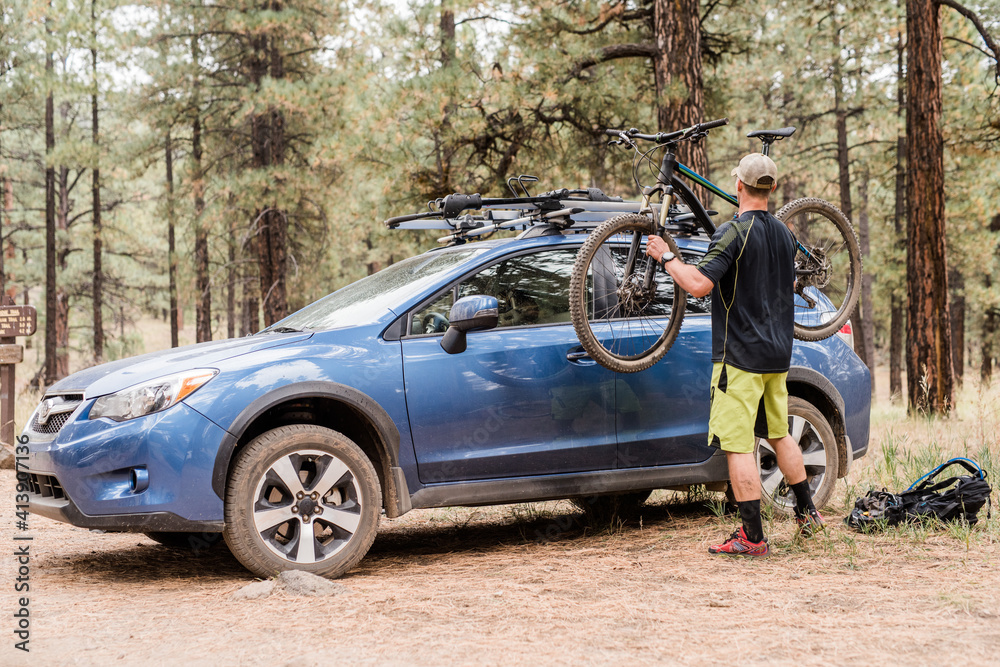 Man taking mountain bike down from car Man taking mountain bike down from car