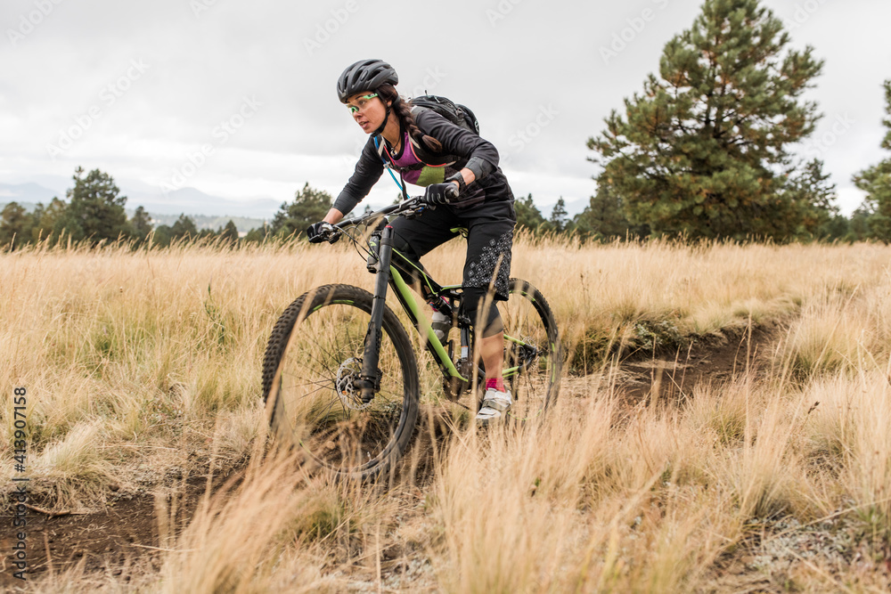 Woman riding mountain bike on meadow trail Woman riding mountain bike on meadow trail