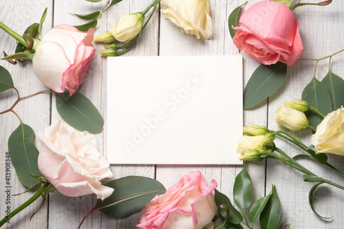 Fototapeta Naklejka Na Ścianę i Meble -  Floral background and blank white card. Eustoma, eucalyptus and pink roses. Holiday concept and copy space.