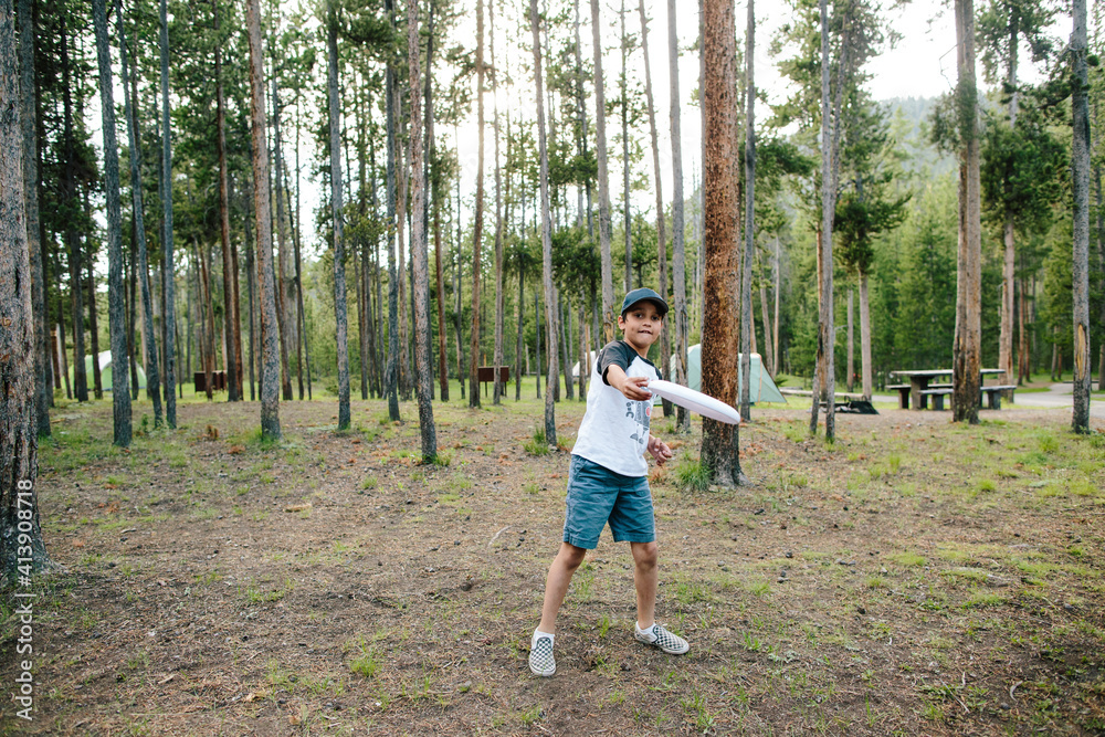 Portrait of boy throwing plastic disc while standing against trees in forest Portrait of boy throwing plastic disc while standing against trees in forest