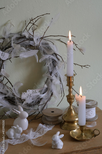 Easter decor on the dresser: porcelain rabbits, Easter wreath of twigs and feathers, copper candlesticks, lace on a spool photo