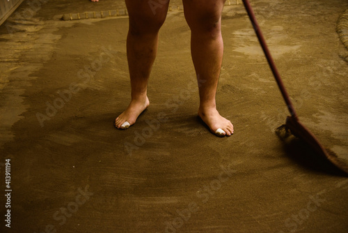 Low section of wrestler sweeping field with broom in sumo beya photo