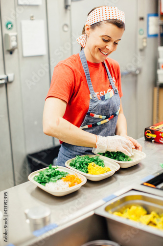 Female chef serving food in plates on kitchen counter at restaurant photo