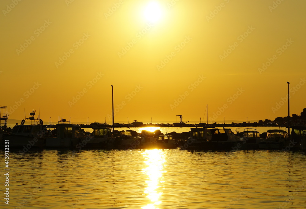 Summer sunset in the picturesque small sea port with mooring boats and yachts Summer sunset in the picturesque small sea port with mooring boats and yachts
