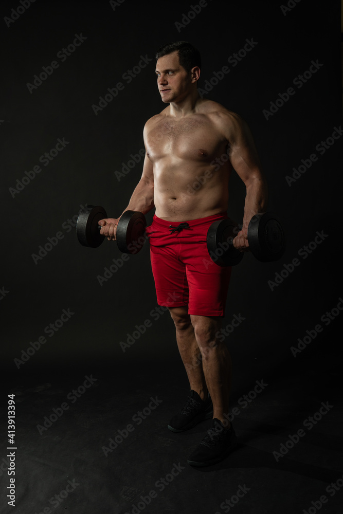 Fitness man presses dumbbells in red panties style beautiful, torso casual background. Male models, successful cool background black bodybuilder