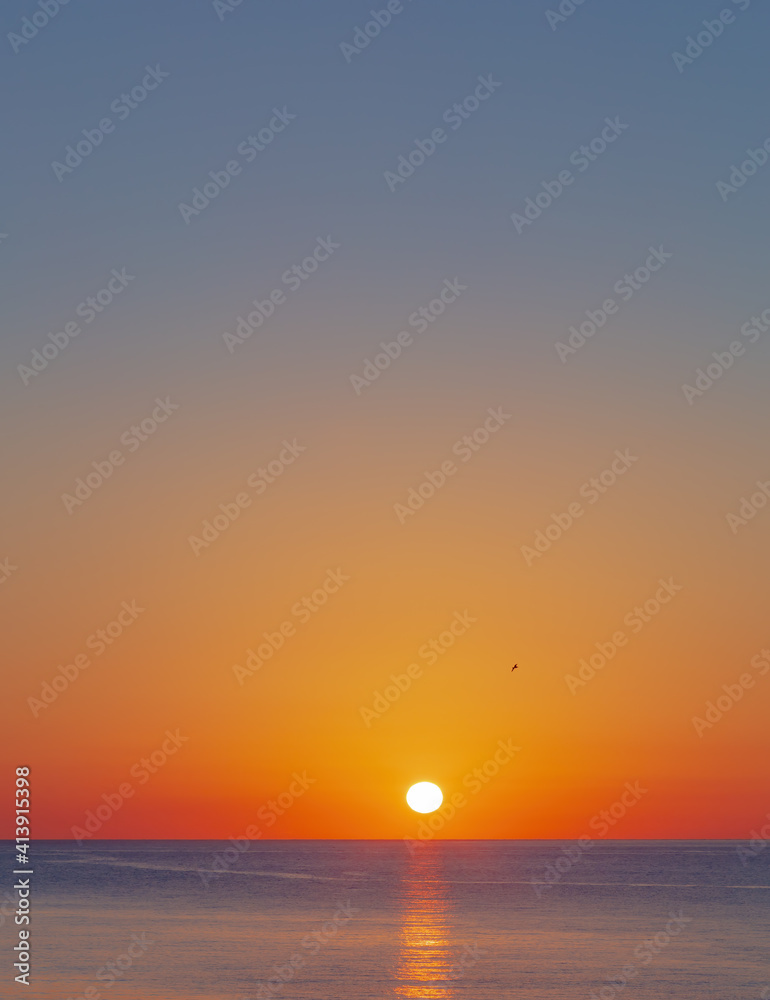 Red sun over the sea, turquoise sky and blue sea at sunrise, early morning in Greece.