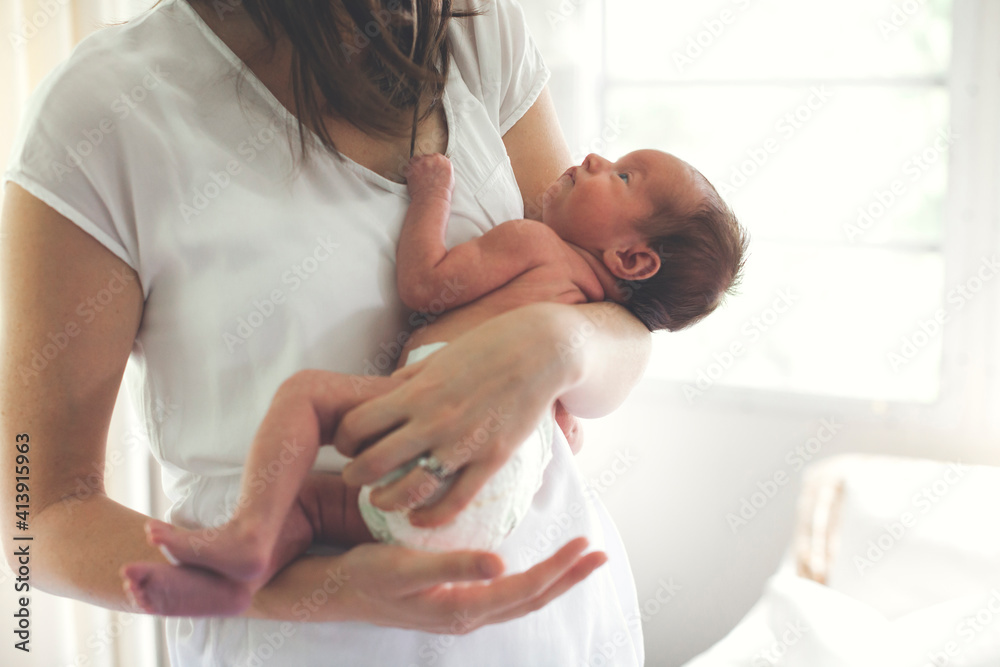Midsection of mother carrying newborn daughter at home Midsection of mother carrying newborn daughter at home
