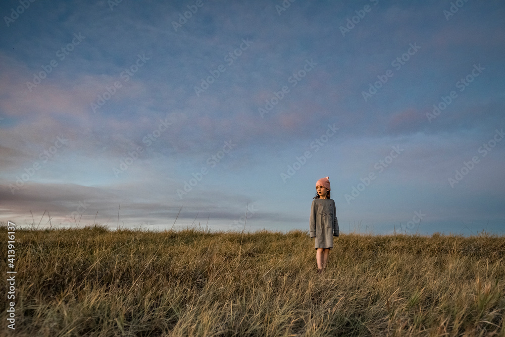 Girl standing on grassy field against sky during sunset Girl standing on grassy field against sky during sunset