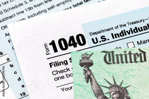 1040 individual income tax return form and tax refund check. Concept of filing taxes, taxable income and tax information. photo