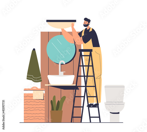 Electrician working in bathroom installing new lamp after renovation of bathtub interior