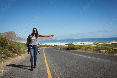 Mixed race woman walking by the road and hitchhiking