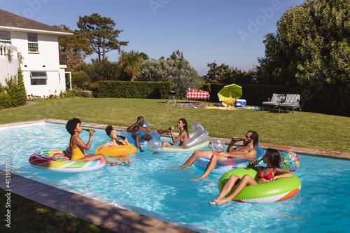 Diverse group of friends having fun playing on inflatables in swimming pool © WavebreakMediaMicro