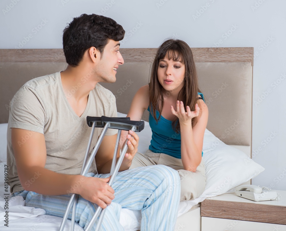 Fototapeta premium Young wife supporting husband on crutch after injury