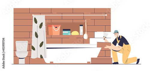 Tiler laying ceramic tiles in modern bathroom. Handyman doing renovation of bathtub