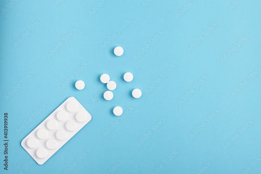 Blister lay on a blue background. White tablets spilling out of package.