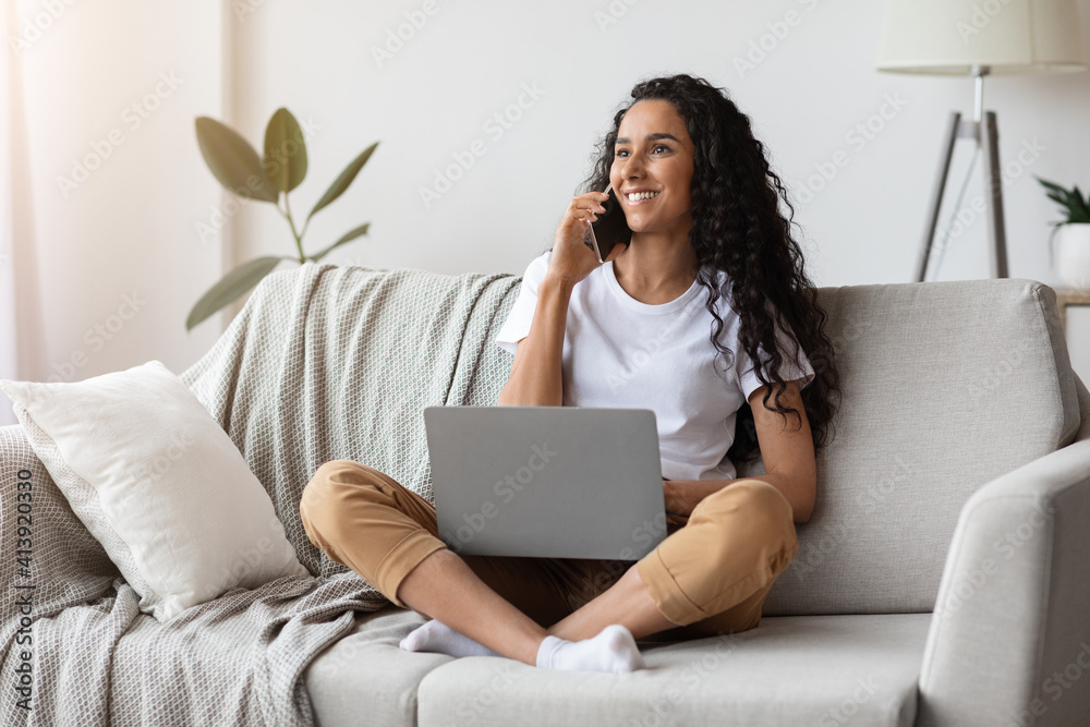 Smiling pretty lady sitting on couch with laptop, having conversation Smiling pretty lady sitting on couch with laptop, having conversation