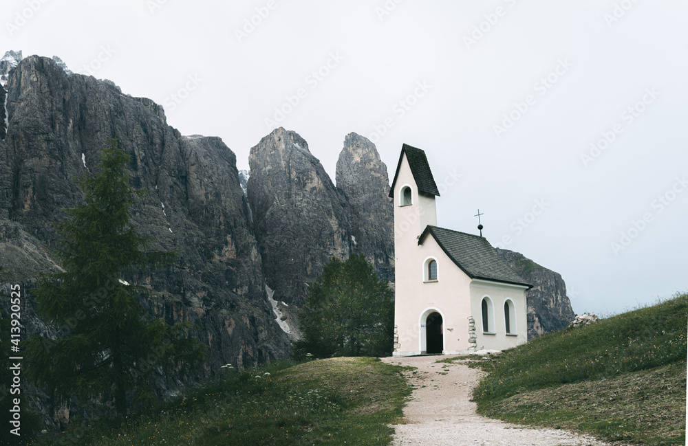 Chapel on the mountain pass. Passo Gardena, Trento Alto Adige, Sella, Dolomites, Italy. Cold summer morning with low clouds.
