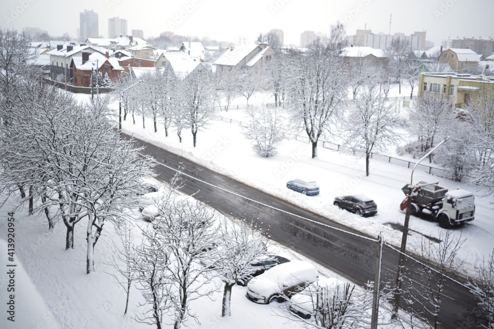 Naklejka premium Snowy winter city view from the window. Snowstorm and snow covered street and cars.