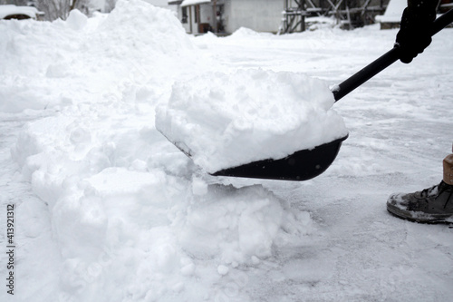 Man with snow shovel cleans sidewalks in winter.