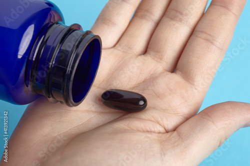 Black capsule spilling out of package on a hand. Heap of pills - medical background