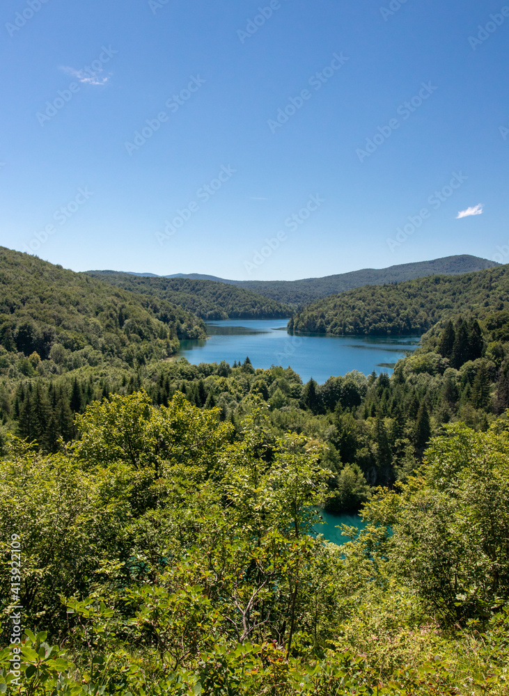 Plitvice Lakes National Park, Coratia: Pamoramic image of the upper lakes with blue sky on a hot summer day. No clouds and lush green forest.
