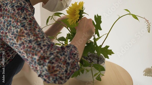 Mujer tocando un girasol cubierto de hojas. Arreglo floral