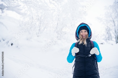 A smiling, warmly dressed tourist on a mountain trail in winter. Active in winter.