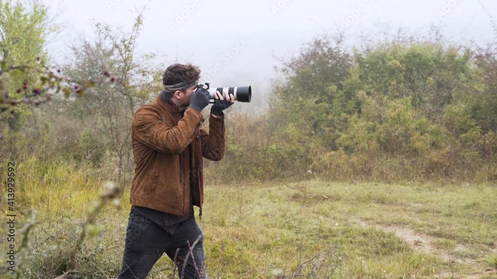 Wildlife photographer with a DSLR camera taking photos in bushes,mist. Wildlife photographer with a DSLR camera taking photos in bushes,mist.