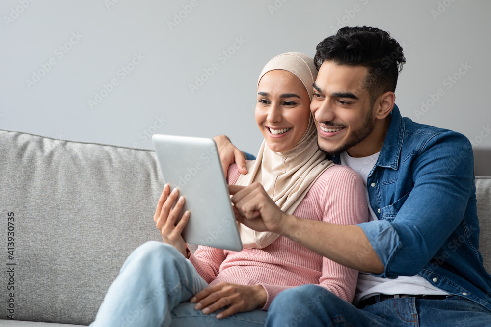 Excited arab guy showing something girlfriend on Internet, using pad