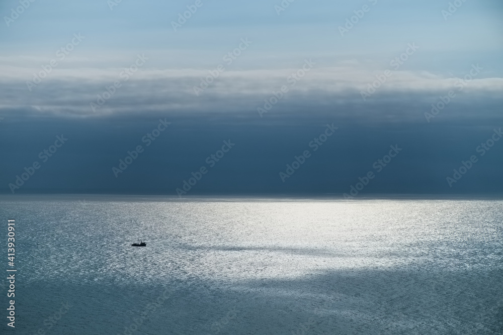 small lone ship in blue ocean sun and clouds small lone ship in blue ocean sun and clouds
