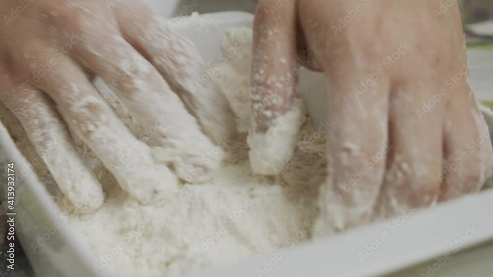 Mixing chicken meat in cooking flour inside small ceramic plate. Close up on chef's hands. Slow motion shot. Mixing chicken meat in cooking flour inside small ceramic plate. Close up on chef's hands. Slow motion shot.