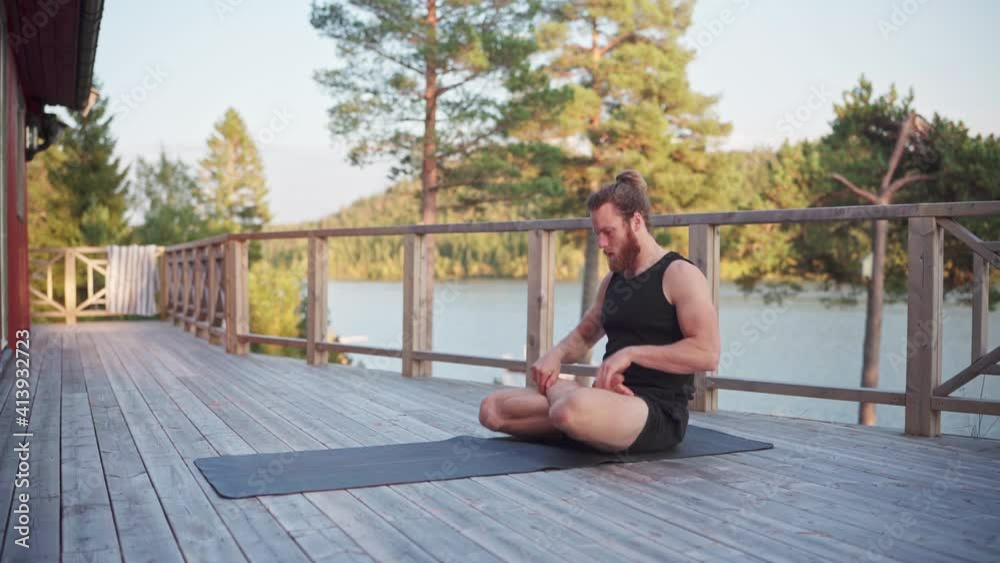 Man Doing Yoga Workout In The Veranda Of Cabin In The Morning. wide shot Man Doing Yoga Workout In The Veranda Of Cabin In The Morning. wide shot