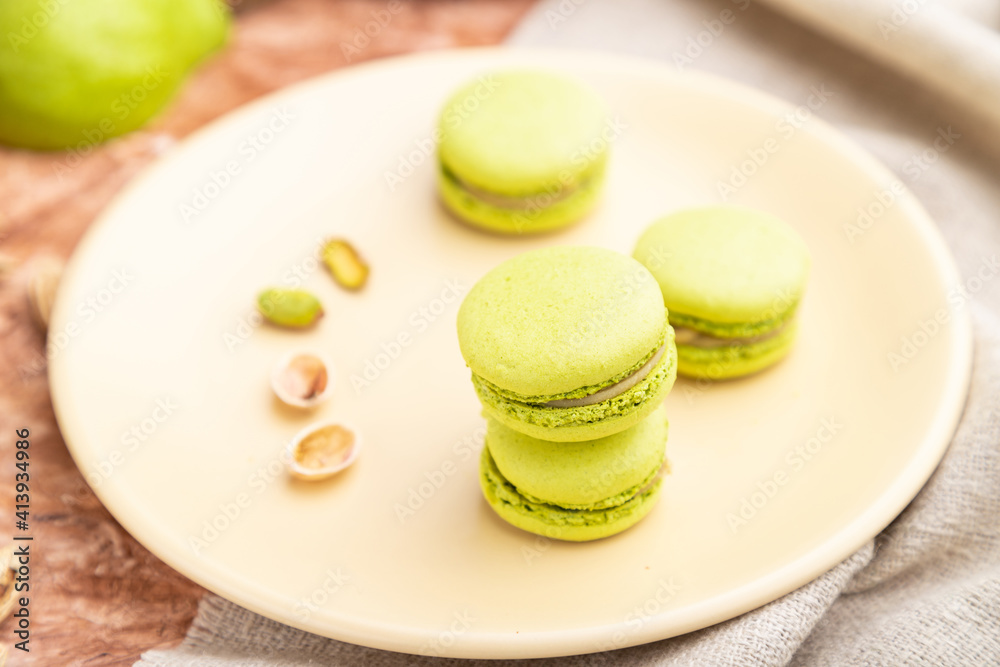 Green macarons or macaroons cakes with cup of coffee on a brown concrete background. Side view, selective focus. Green macarons or macaroons cakes with cup of coffee on a brown concrete background. Side view, selective focus.