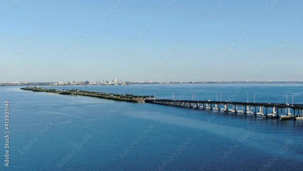 Aerial Drone Panning Shot Over Blue Bay Water Towards a Bridge with Traffic and Skyline in the Distance. Late Afternoon. Clearwater Memorial Causeway Florida
Aerial Drone Panning Shot Over Blue Bay Water Towards a Bridge with Traffic and Skyline in the Distance. Late Afternoon. Clearwater Memorial Causeway Florida