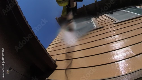 Cleaning the dirty wood siding of the house using high pressure water jet outdoor, POV photo