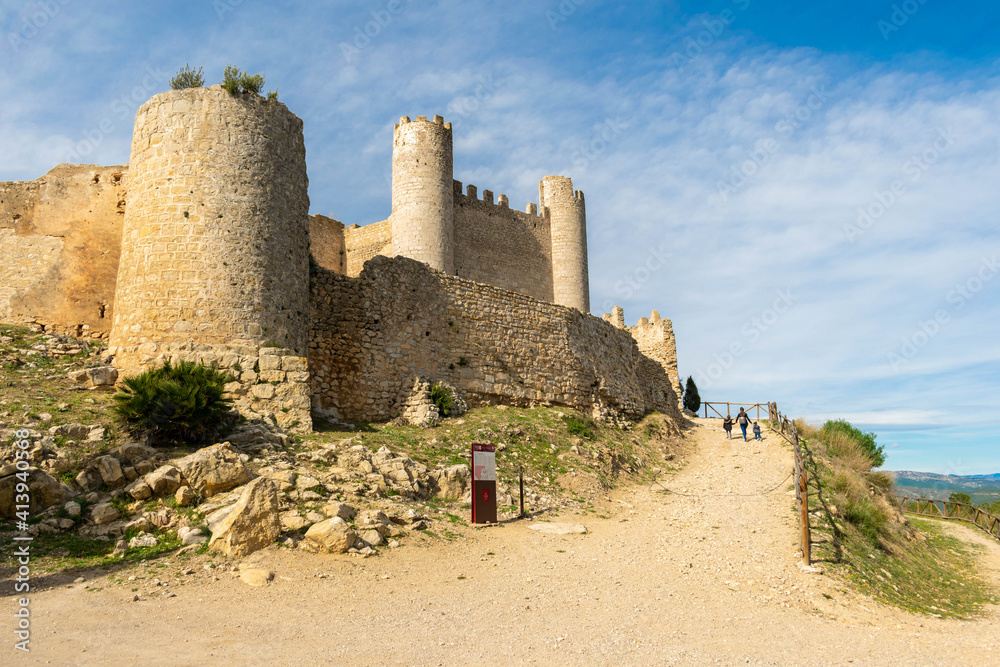 familia de mujer y dos niños cogidos de la mano, paseando delante de las ruinas del castillo de Alcalá de  xivert, provincia de Castellón de la plana , España , 