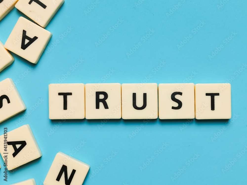 TRUST word made from square letter tiles on blue background. TRUST word made from square letter tiles on blue background.