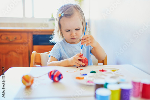 Adorable little girl painting eggs for Easter