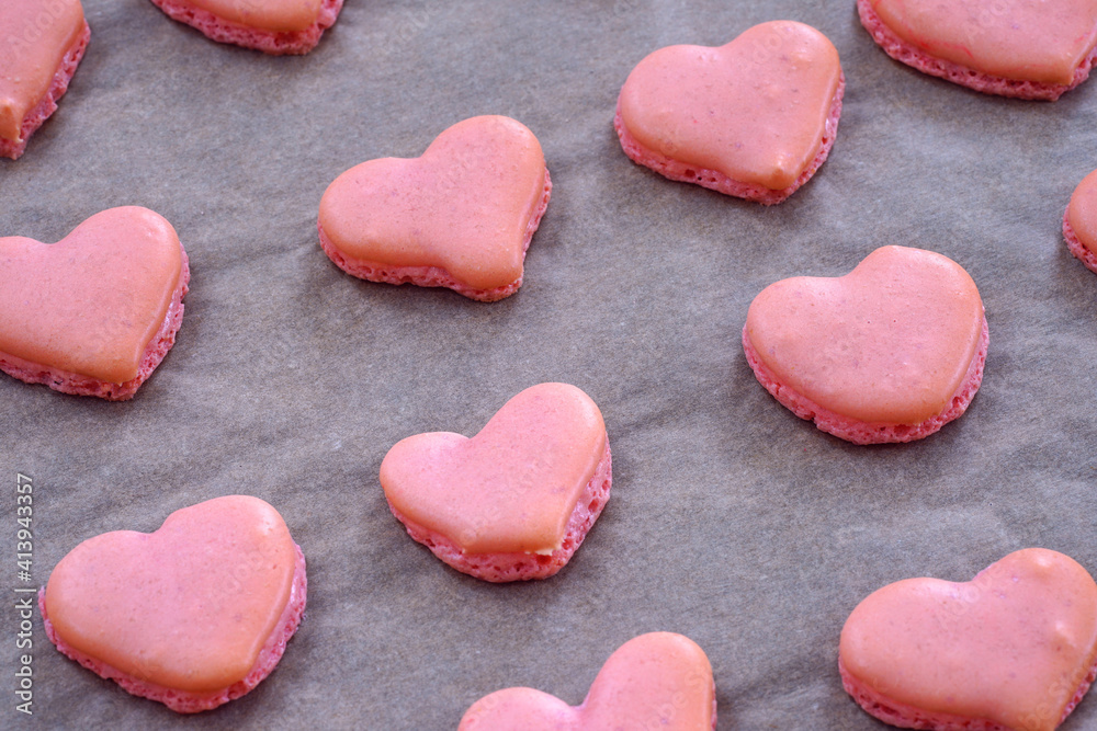Obraz premium Pink heart homemade macaron cookies on parchment paper on a baking sheet