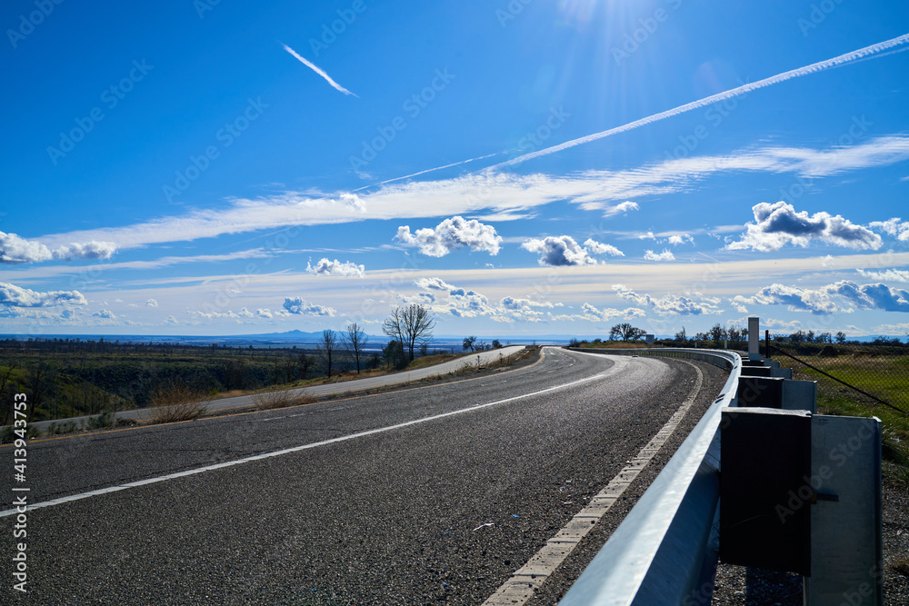 Fototapeta premium Road in the Mountains with Blue Skies and White Clouds; East View of Skyway Road located in Paradise California. 