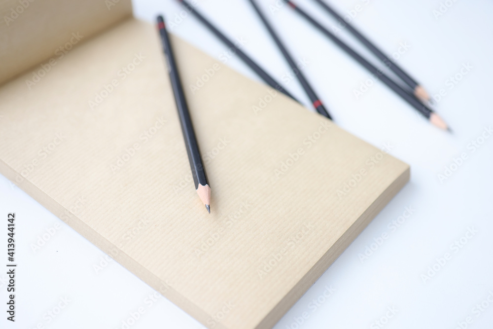 There is notebook and black pencils on table There is notebook and black pencils on table