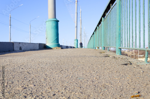 close-up view of the asphalt sidewalk and green fence on the right
