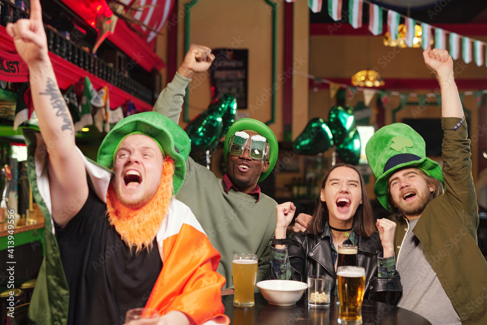 Group of young excited football fans expressing triumph during football game