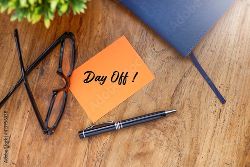 Message on Day Off on the piece of paper with a pen, eyeglasses, and a notebook on the wooden table  photo